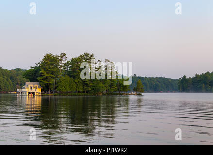 Un petit chalet au bord du lac sur une île dans le Muskoka, Ontario, au lever du soleil. Banque D'Images