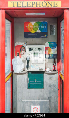 Boîte de téléphone rouge abandonnés à Manchester avec des graffitis et des bouteilles vides d'alcool Banque D'Images