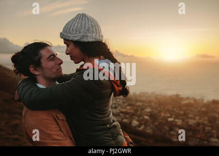 Couple romantique et à la recherche à l'autre avec amour. Femme Homme portant sur journée d'hiver. Les deux sur sommet de montagne au coucher du soleil. Banque D'Images