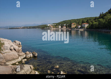 Rochers sur la côte de la baie de la mer Adriatique à l'avant-plan. Avec l'assainissement de l'eau visible en bas. Maisons et hôtels dans l'arrière-plan. Ciel bleu clair. Omis Banque D'Images