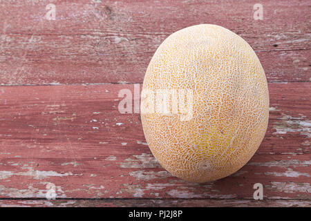 Tout un melon mûr sur une table marron foncé Banque D'Images