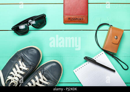 Set de voyage, passeport, chaussures, lunettes de soleil, appareil photo. on a wooden surface turquoise, une vue de dessus Banque D'Images