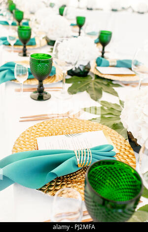 L'intérieur de tente pour diner de mariage, prêts pour les clients. Servi en plein air table de banquet ronde décorée de renom dans l'hydrangea fleurs, des plats d'or et vert. Concept de restauration Banque D'Images