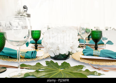 L'intérieur de tente pour diner de mariage, prêts pour les clients. Servi en plein air table de banquet ronde décorée de renom dans l'hydrangea fleurs, des plats d'or et vert. Concept de restauration Banque D'Images