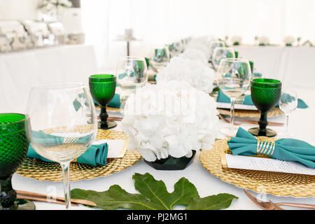 L'intérieur de tente pour diner de mariage, prêts pour les clients. Servi en plein air table de banquet ronde décorée de renom dans l'hydrangea fleurs, des plats d'or et vert. Concept de restauration Banque D'Images