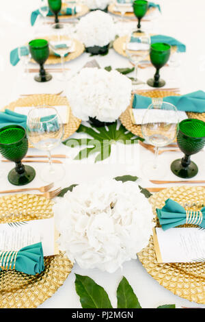 L'intérieur de tente pour diner de mariage, prêts pour les clients. Servi en plein air table de banquet ronde décorée de renom dans l'hydrangea fleurs, des plats d'or et vert. Concept de restauration Banque D'Images