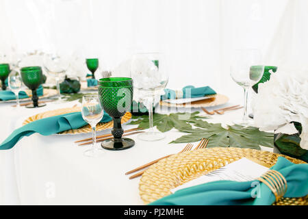 L'intérieur de tente pour diner de mariage, prêts pour les clients. Servi en plein air table de banquet ronde décorée de renom dans l'hydrangea fleurs, des plats d'or et vert. Concept de restauration Banque D'Images