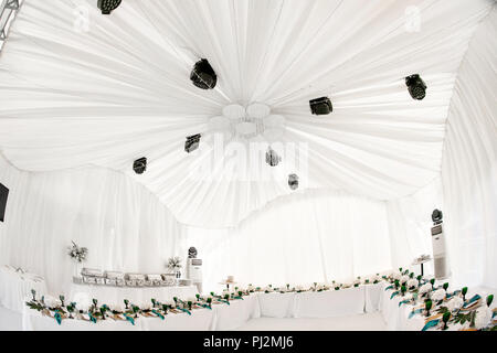 L'intérieur de tente pour diner de mariage, prêts pour les clients. Servi en plein air table de banquet ronde décorée de renom dans l'hydrangea fleurs, des plats d'or et vert. Concept de restauration Banque D'Images