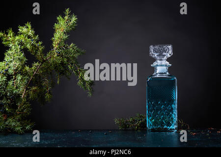 Carafe en cristal bleu Gin et genièvre baies avec la direction générale sur un fond noir. Copie de l'espace pour votre texte. Banque D'Images