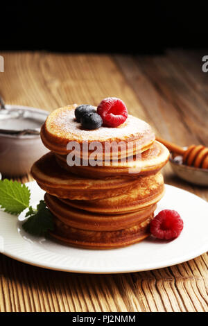 Crêpes aux fruits rouges et sirop d'érable sur la table rustique. Banque D'Images