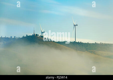 La ferme éolienne de deux éoliennes sur le dessus une colline, tôt le matin, nuage de brouillard. Concept d'économies d'énergie, le développement durable Banque D'Images