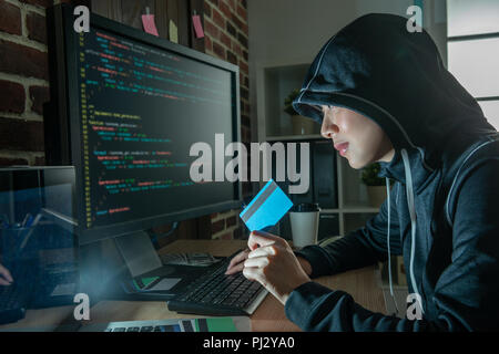 Jolie hacker prêt pour les crimes sur Internet. smiling and holding credit card volés par d'autres. Banque D'Images