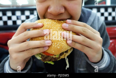 Jeune personne manger burger Banque D'Images