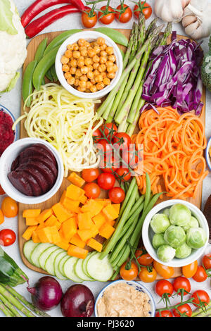 Voir ci-dessus des ingrédients pour la salade, légumes colorés, carotte, courgette, chou, pois chiches, asperges, concombres et tomates, sur le sol en bois Banque D'Images