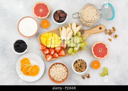 Vue de dessus du petit-déjeuner sain avec l'avoine, de la variété des fruits, fraises, mangue, raisin, servi sur la table blanche, selective focus Banque D'Images