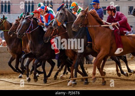 Jockeys vêtus de costumes colorés qui représentent leur Contradas prendre part à l'un des six courses d'essai qui précèdent le Palio, Sienne, Italie Banque D'Images