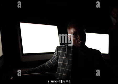 Young businessman sitting in computer room at night Banque D'Images