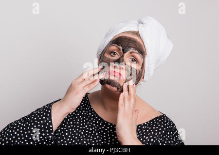 Une triste femme surpoids avec masque facial noir sur son visage dans un studio. Banque D'Images