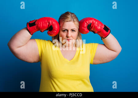 Portrait d'une femme en surpoids avec des gants de boxe rouge en studio. Banque D'Images