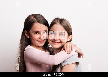 Deux petites filles debout dans un studio., serrant. Banque D'Images