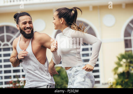 Ville d'exécution couple jogging à l'extérieur. La formation à l'extérieur de glissières à Brooklyn avec Manhattan, New York City dans l'arrière-plan. Mettre en place de remise en forme, couple multiracial Asian Woman, man. Banque D'Images