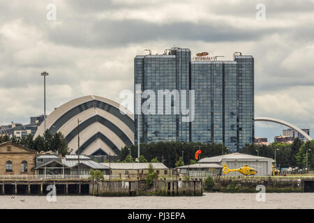 Glasgow, Scotland, UK - 17 juin 2012 : Crown Plaza Hotel et l'Armadillo sec et une partie de la Clyde Arc sous les nuages. Hélicoptère jaune sur la Rive Banque D'Images