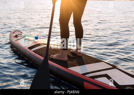 Femme avec une palette sur le tableau noir. Les jambes d'une fille mince sur stand up paddle board. Banque D'Images