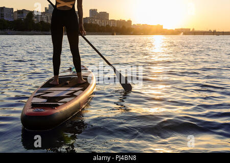 Femme avec une palette sur le tableau noir. Les jambes d'une fille mince sur stand up paddle board. Banque D'Images