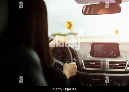 Femme au volant voiture avec signe de courbe prononcée de l'avant sur la route Banque D'Images