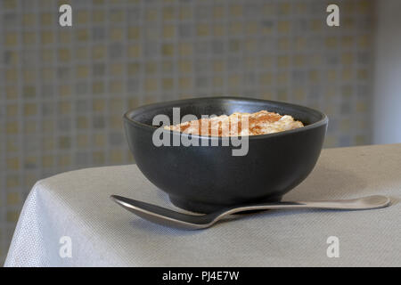 Juste cuit dans le porridge bio authentique bol brun sur table de cuisine. De cannelle et une cuillère. L'avoine à grains entiers. Banque D'Images