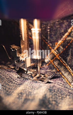 Jeans réparation sur la machine à coudre. Vue sur le tissu, l'aiguille et fil. Du vrai flou de mouvement. Éclairé par la lampe à incandescence. Les jeans sont un type Banque D'Images