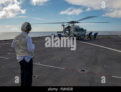 180829-N-A530-0256 de l'OCÉAN ATLANTIQUE (Aug. 29, 2018) - Premier maître de Manœuvre principal Neal baronnet observe comme marins enlever les chaînes d'un MH-60S Sea Hawk avant de partir au poste de pilotage de la station d'amphibie Navire de débarquement USS Fort McHenry (LSD 43) Groupe aéronaval pendant quatre (4) CSG groupe amphibie, Marine Expeditionary Unit Exercise (ARGMEUEX). Groupe amphibie Kearsarge et 22e Marine Expeditionary Unit sont l'amélioration de l'intégration interarmées, la létalité et capacités collectives de l'équipe de Navy-Marine corps grâce à une planification et l'exécution des Banque D'Images