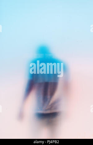 Silhouette de l'homme masculin déprimé triste méconnaissable, la tête en bas, derrière une vitre sale window Banque D'Images