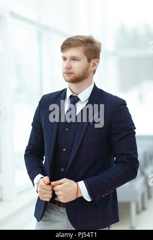 Pensive young businessman standing près de la fenêtre du bureau Banque D'Images