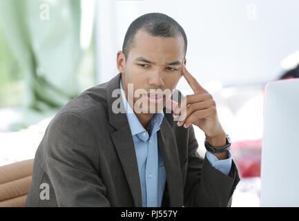 Portrait of pensive businessman assis derrière un bureau. Banque D'Images