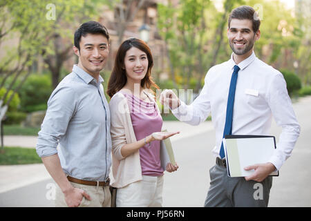 Happy young couple recevant clé de la maison de l'agent immobilier Banque D'Images