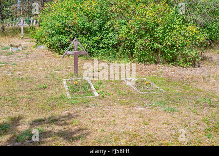 Vieux cimetière abandonné sous le soleil de l'été. Croix en bois patiné. Banque D'Images