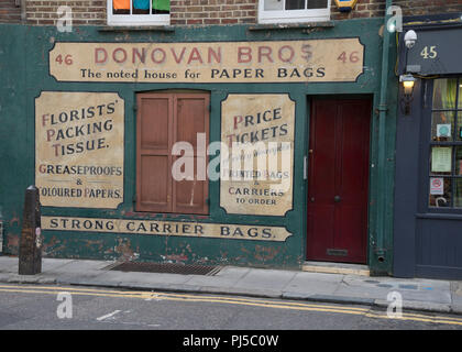 Ancien années 30 enseignes commerciales sur un mur par l'église de Spitalfields dans la ville de London,UK Banque D'Images