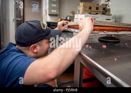 180826-N-SO730-0266 de l'OCÉAN ATLANTIQUE (Aug. 26, 2018) 2ème classe spécialiste culinaire Tyler Silva, à partir de la kuna, Idaho, vérifie la qualité du gâteau de feuille pour l'égalité des femmes journée organisée par le Comité du patrimoine de la diversité américaine Respect à bord du porte-avions USS George H. W. Bush (CVN 77). Le navire est en cours d'entraînement de routine des exercices pour maintenir l'état de préparation de l'opérateur. (U.S. Photo par marine Spécialiste de la communication de masse 3e classe Joe Boggio) Banque D'Images