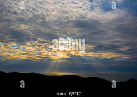 Lumière du soir, avec sa silhouette pointe derniers rayons de soleil à travers des nuages fragmentés à l'éclairage de l'océan. Coucher de soleil sur l'horizon Banque D'Images