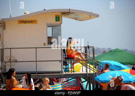 Un sauveteur RNLI observe avec soin les nageurs dans la mer depuis son poste à la plage de Bournemouth, au Royaume-Uni Banque D'Images