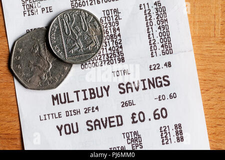 Le montant de l'épargne Multibuy énumérés sur un ticket de caisse de supermarché avec des pièces à valeur de montant total enregistré. Banque D'Images