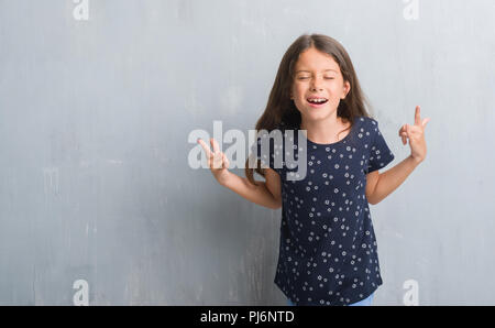 Les jeunes enfants hispaniques plus grunge mur gris criant avec crazy expression faisant rock symbole avec les mains. Music star. Concept lourd. Banque D'Images