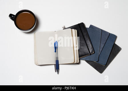 Ordinateur portable usé isolés empilés avec café et journaux stylo Banque D'Images
