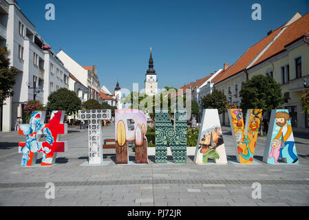 TRNAVA, Slovaquie - 29 août 2018 : zone piétonne avec hashtag original art. Renaissance tower et l'église de la Sainte Trinité en arrière-plan. Banque D'Images