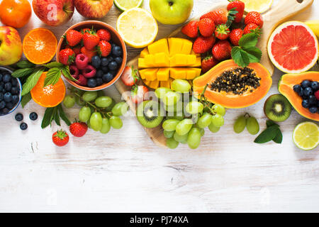 Vue supérieure de couleur arc-en-ciel de fruits, fraises, bleuets, mangue, orange, pamplemousse, banane, pomme, raisins, kiwis sur le fond blanc, c Banque D'Images