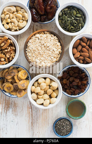 Muesli muesli sain ingrédients, d'avoine, noix, amandes, noix de cajou, graines de citrouille, raisins, bananes, dattes, miel, vue du dessus Banque D'Images