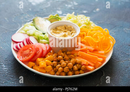 Assiette vegan arc-en-ciel, les pois chiches et les légumes sur le fond bleu Banque D'Images