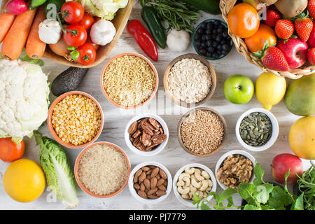 Variété de fruits et légumes, les céréales, les noix sur la table en bois blanc, vue du dessus, selecitve point. Panier de fraises, pommes, oranges, kiwi, b Banque D'Images