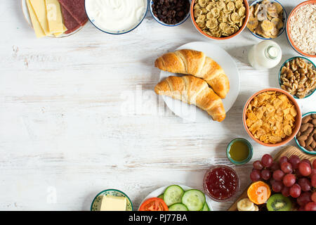 Vue supérieure du petit-déjeuner continental sain, jambon, fromage, céréales, pain grillé, noix, confitures, légumes, croissants, selective focus, copier du texte pour l'espace Banque D'Images